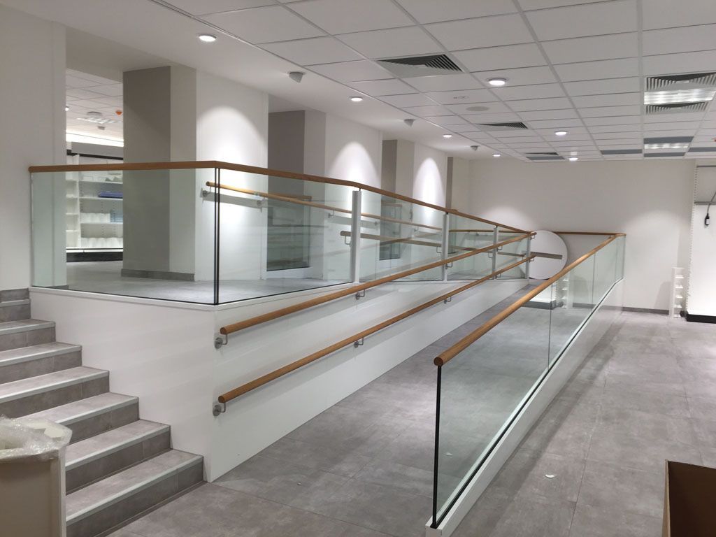 Ein langer Flur mit Treppe und Glasgeländer.