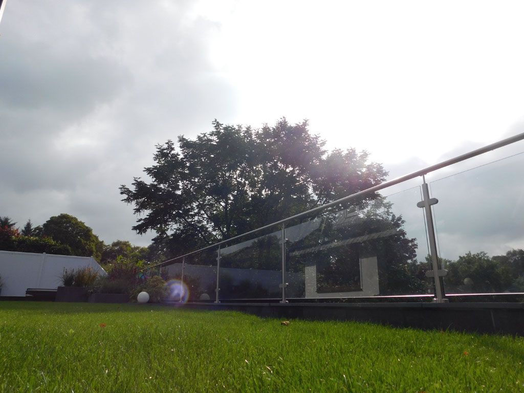 Eine Wiese mit einem Glasgeländer und einem Baum im Hintergrund