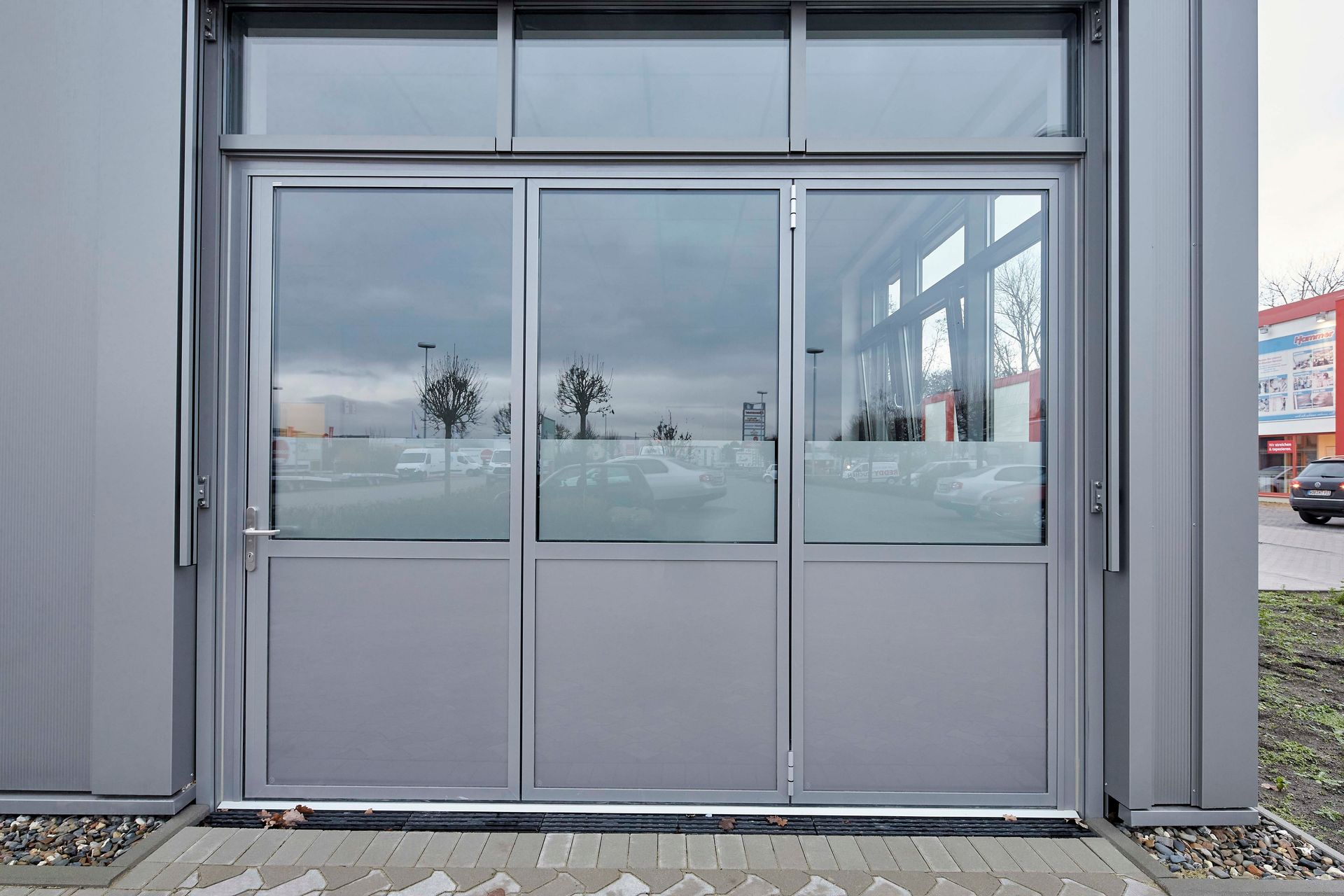 Ein Garagentor mit vielen Fenstern und einem davor geparkten Auto.