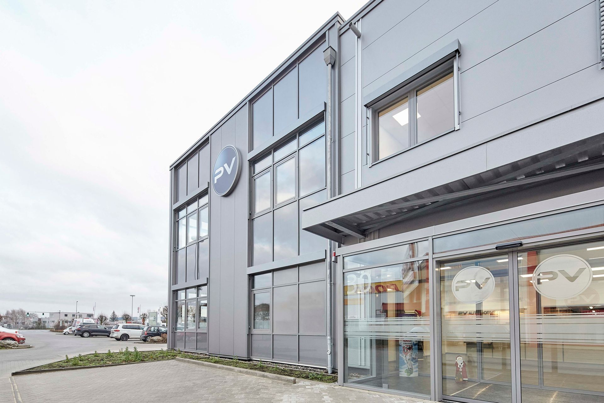 Ein großes Gebäude mit vielen Fenstern und vielen davor geparkten Autos.