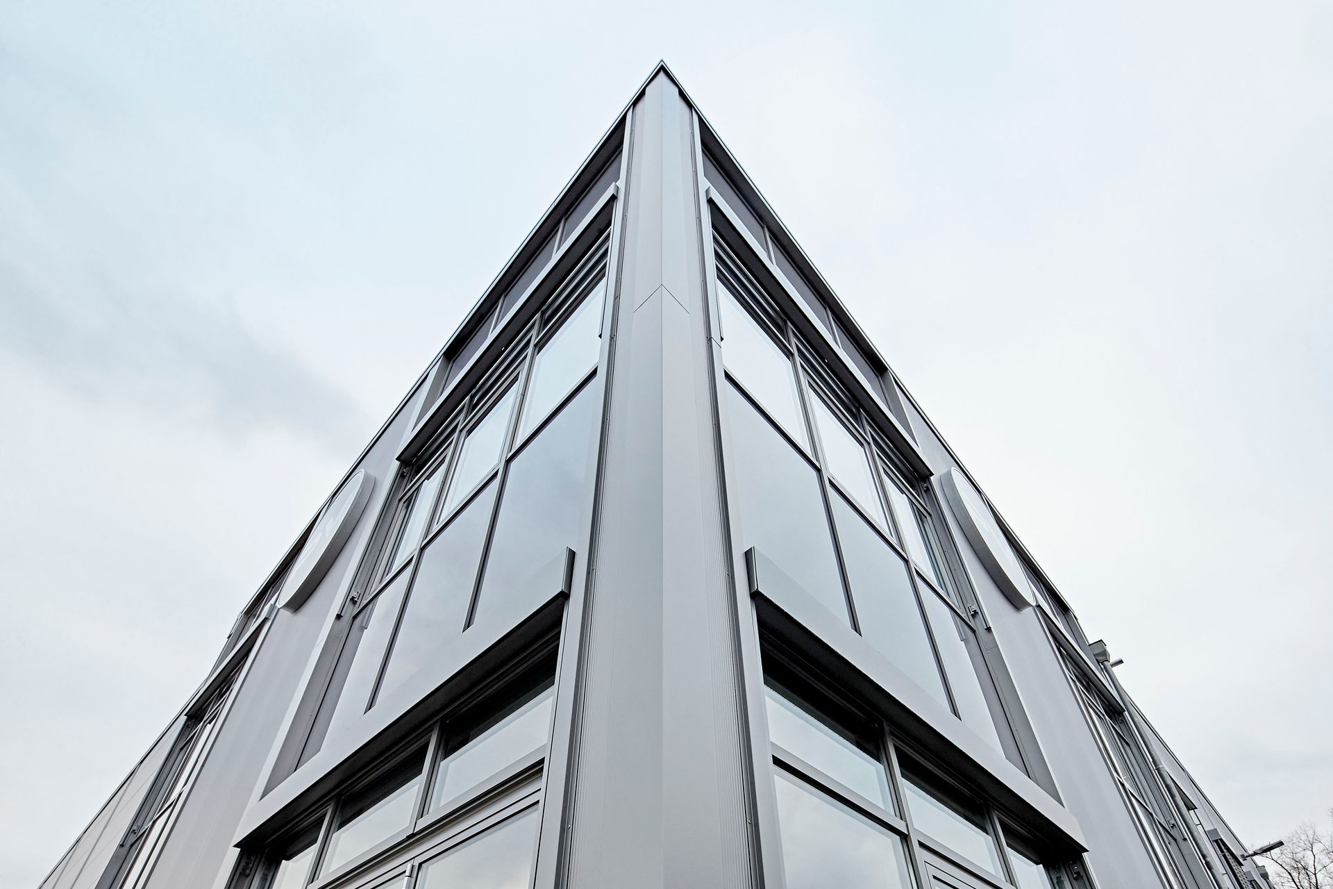 Blick nach oben auf die Ecke eines Gebäudes mit vielen Fenstern.