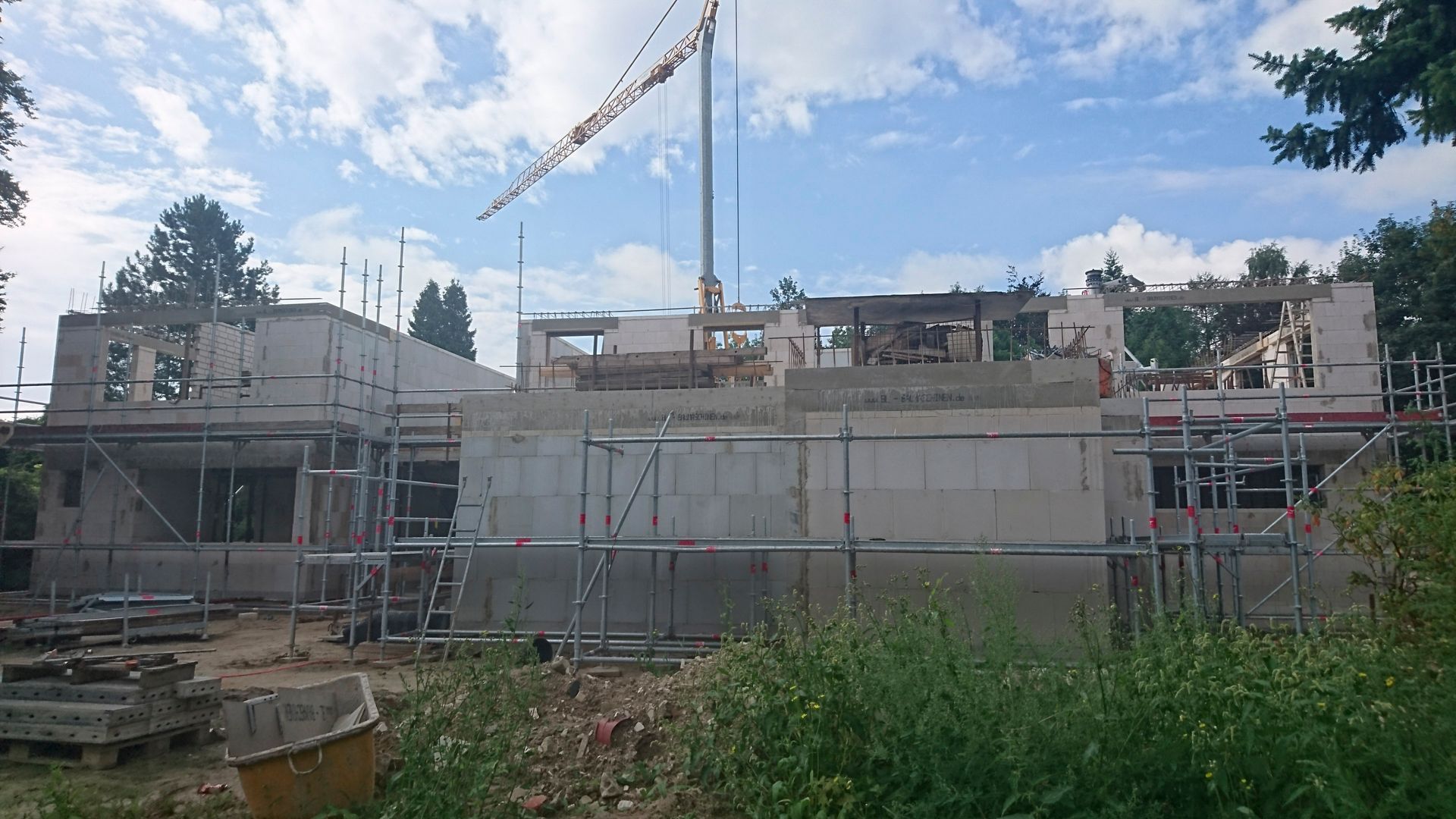 Ein im Bau befindliches Gebäude mit Gerüst und einem Kran im Hintergrund.