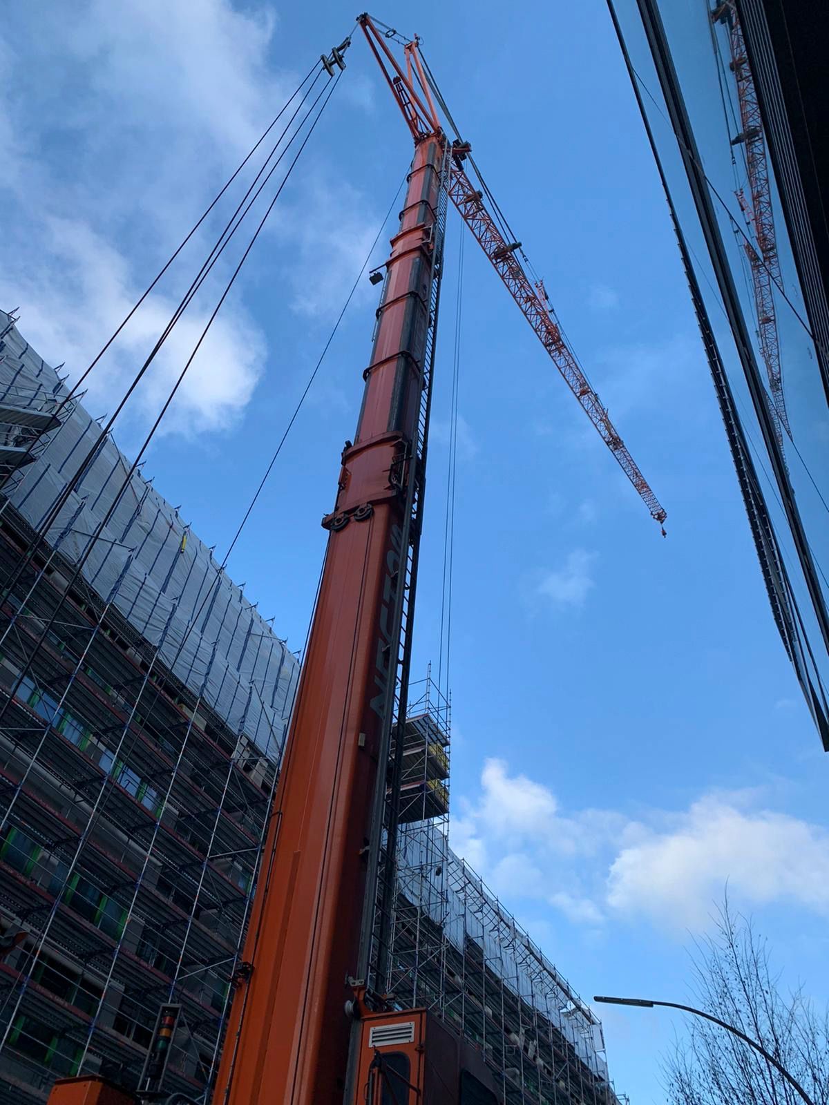 Ein großer orangefarbener Kran steht vor einem im Bau befindlichen Gebäude.