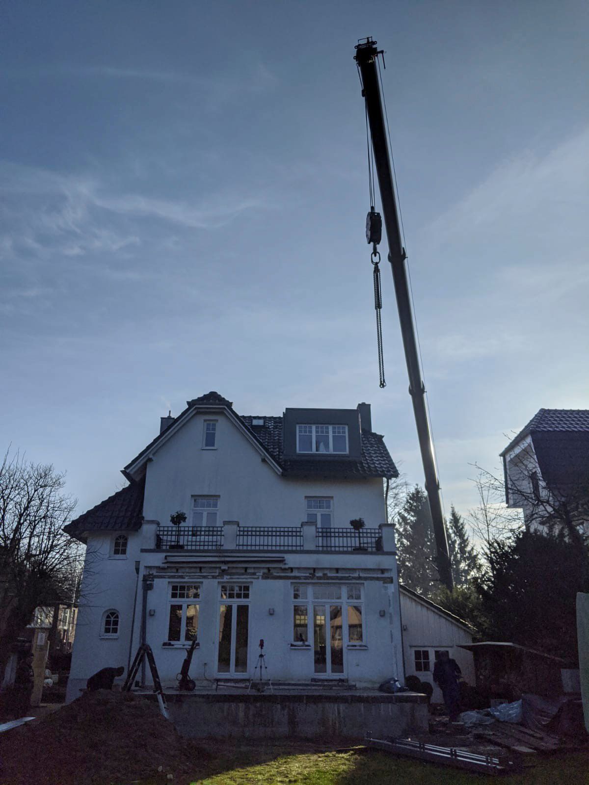 Ein großer Kran hebt das Dach eines Hauses an