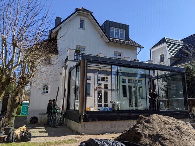 Ein großes weißes Haus mit einem Glasdach und einem großen Erdhaufen davor.