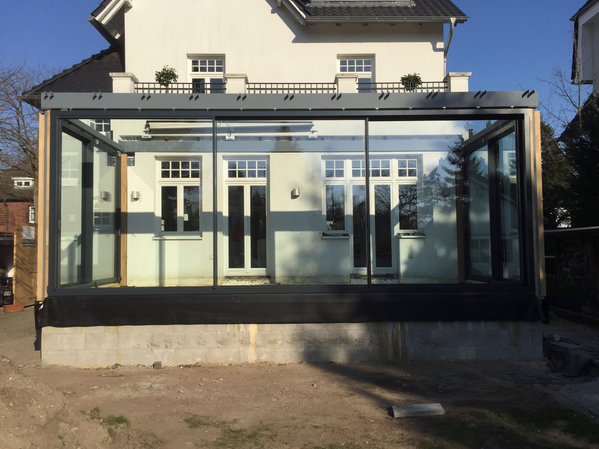 Ein weißes Haus mit einem großen Glasgebäude davor