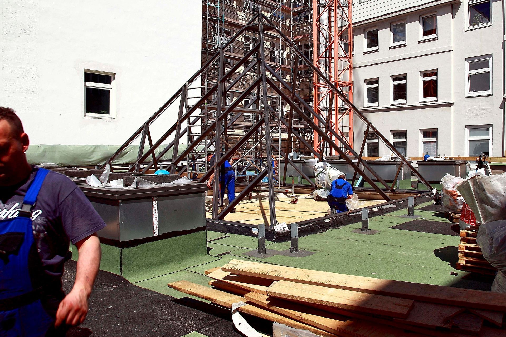Ein Mann im blauen Overall steht vor einem im Bau befindlichen Gebäude