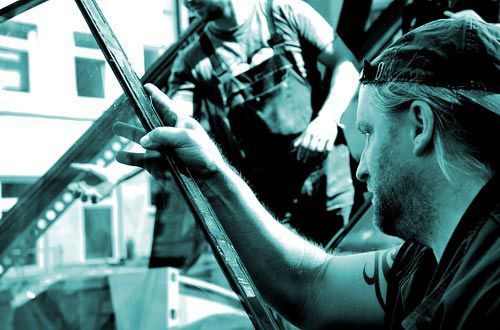 Ein Mann mit einer Baseballkappe arbeitet an einem Autofenster.