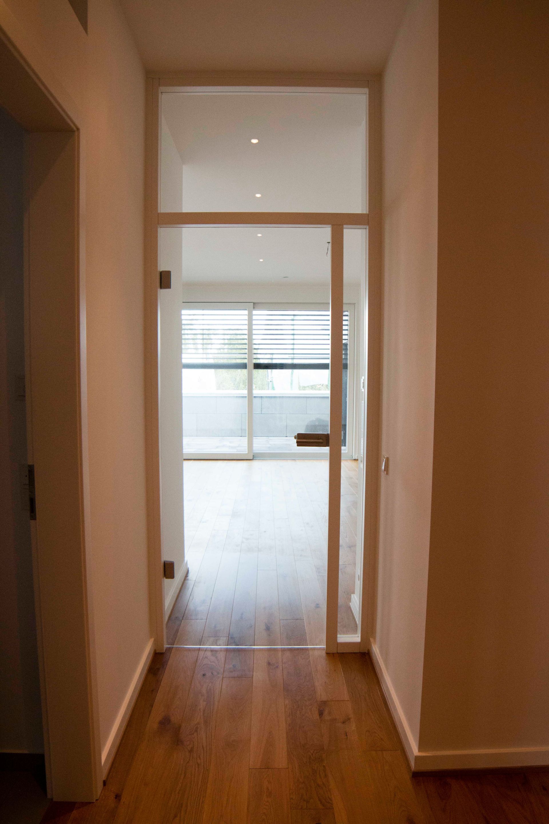 Ein Flur mit einer Glastür, die zu einem Wohnzimmer führt