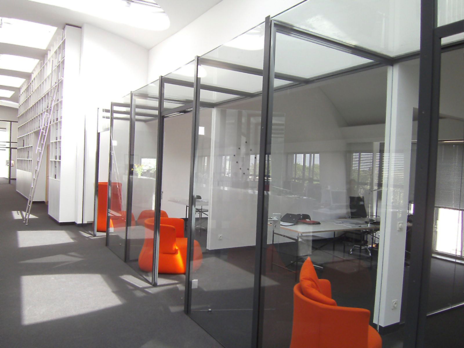 Eine Reihe von Kabinen in einem Büro mit orangefarbenen Stühlen