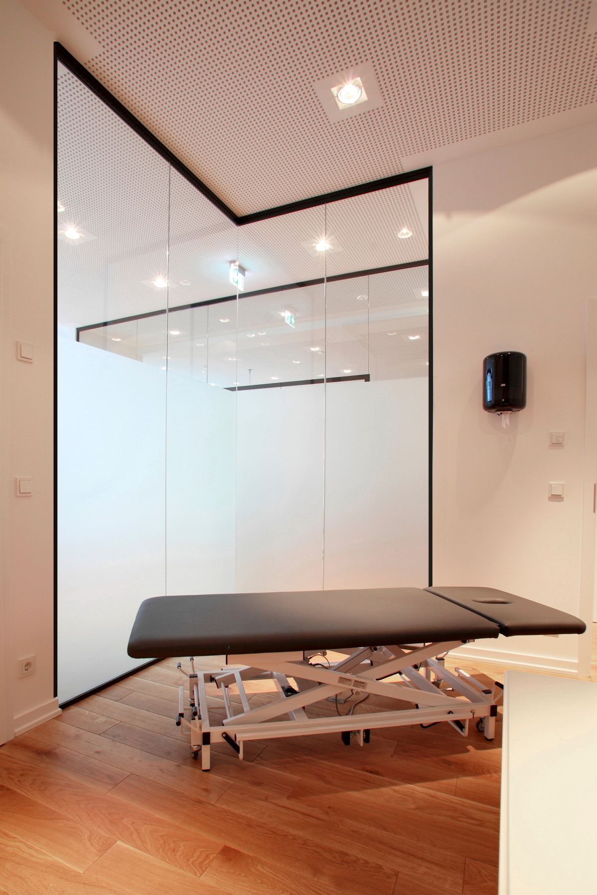 In einem Raum mit Glaswand steht ein Krankenbett.
