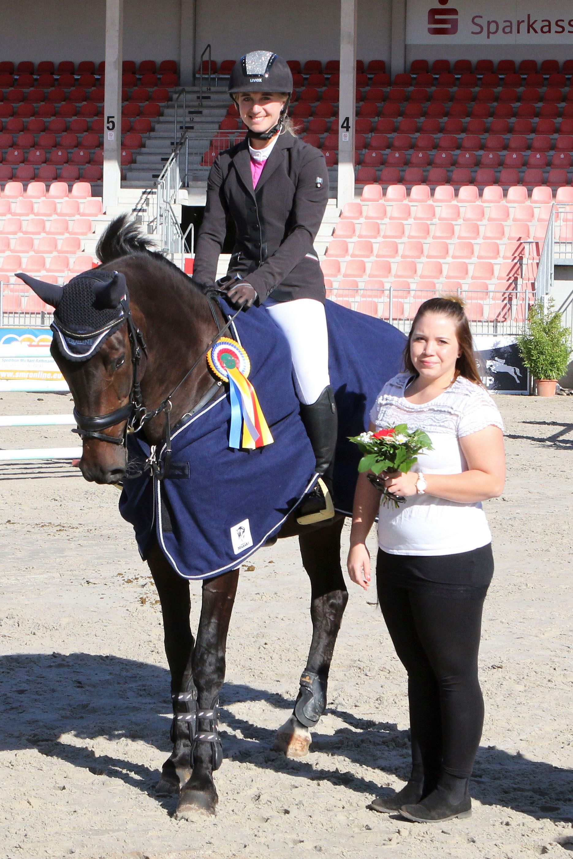 Eine Frau reitet auf einem Pferd neben einer Frau, die Blumen hält.