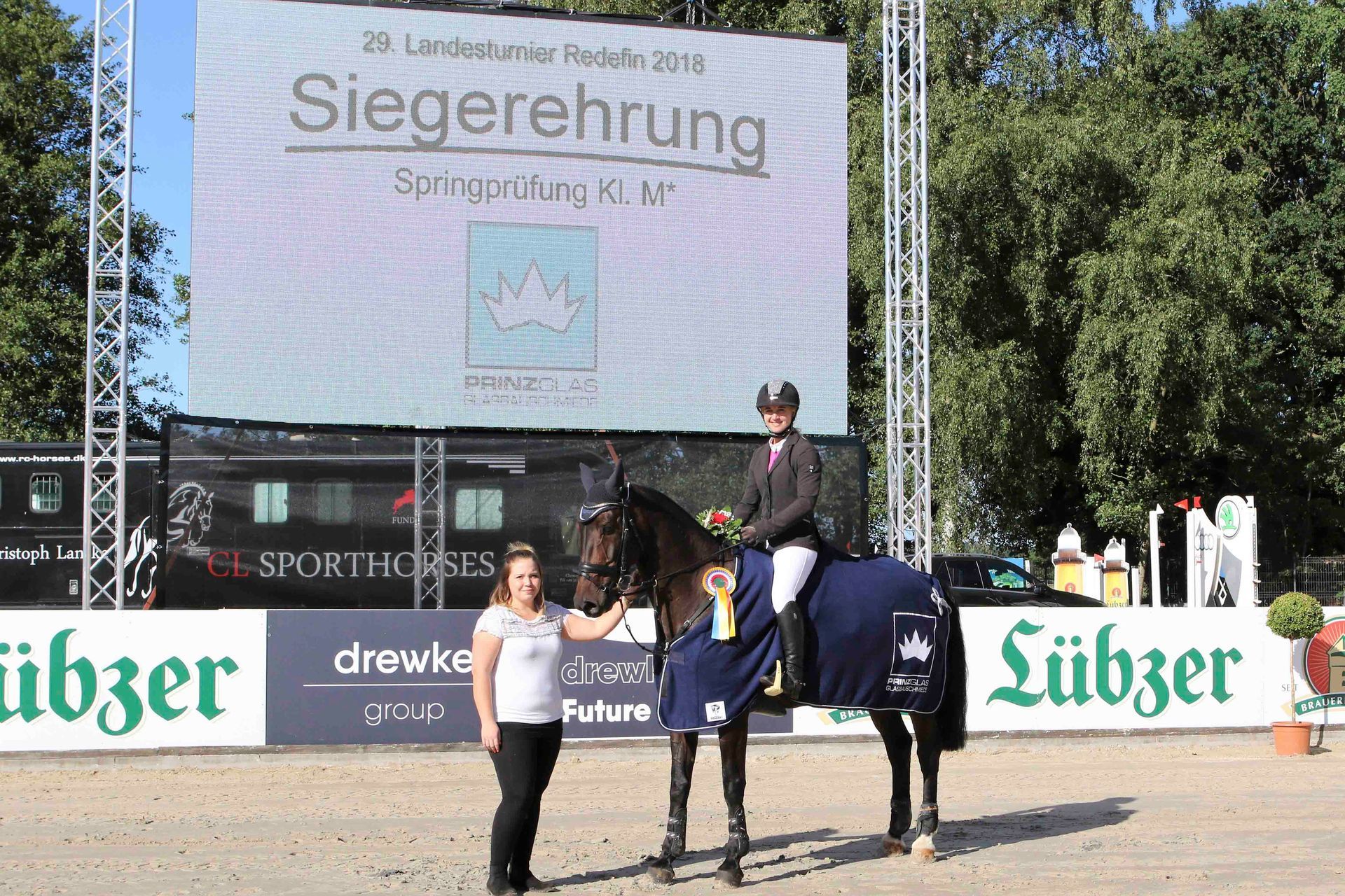 Eine Person, die auf einem Pferd vor einem Schild mit der Aufschrift „Siegerung“ reitet