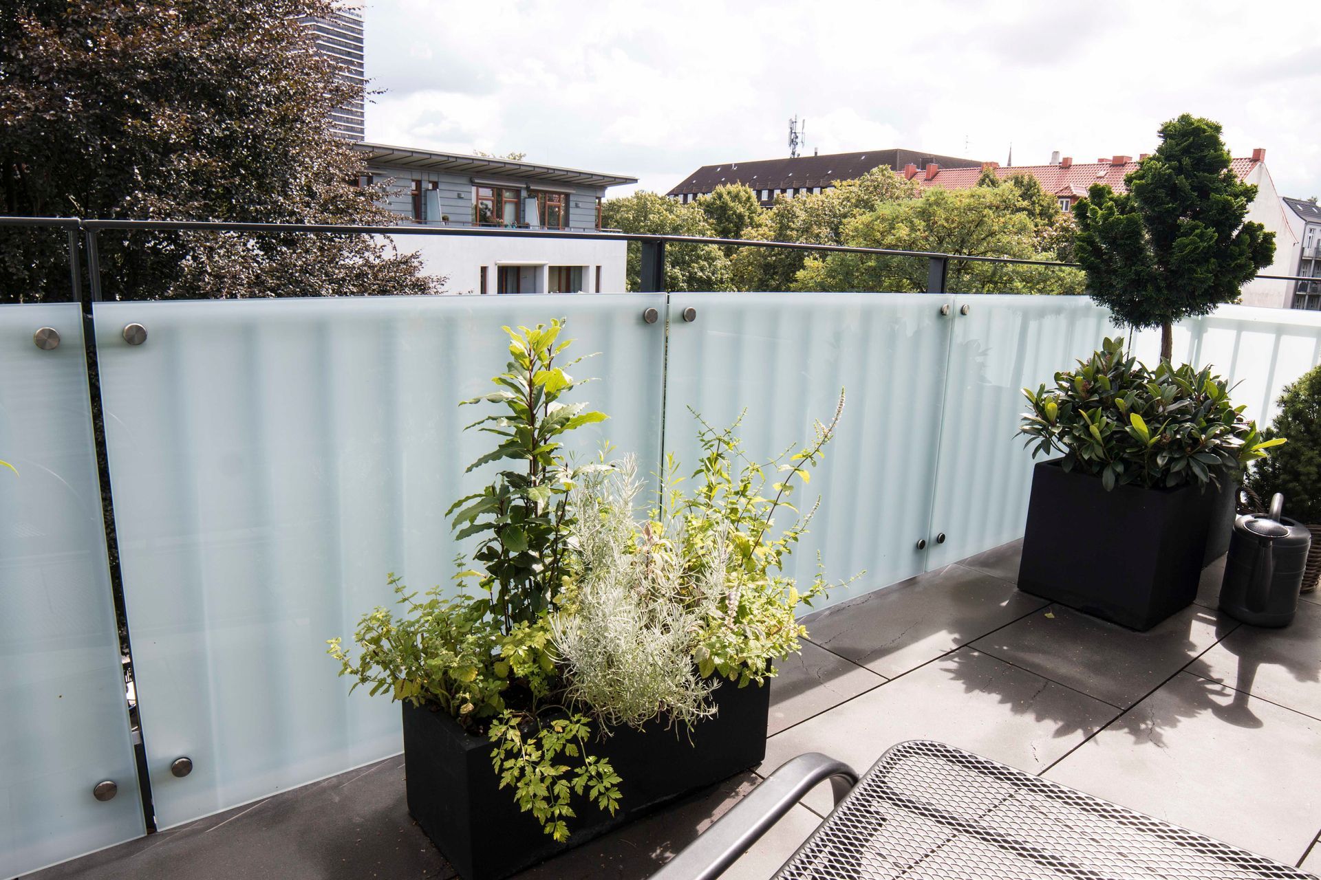 Ein Balkon mit Glaszaun und Topfpflanzen