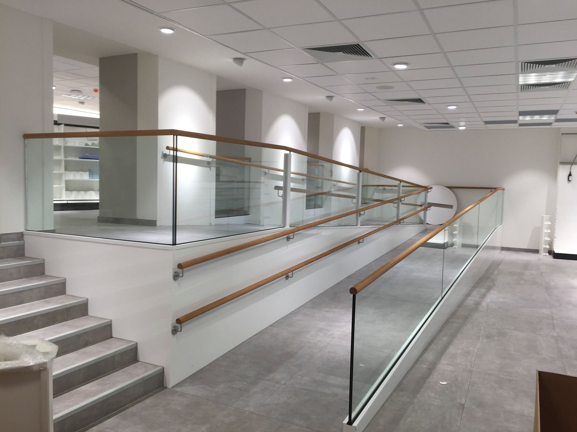 Eine Treppe mit Glasgeländer und Holzhandläufen