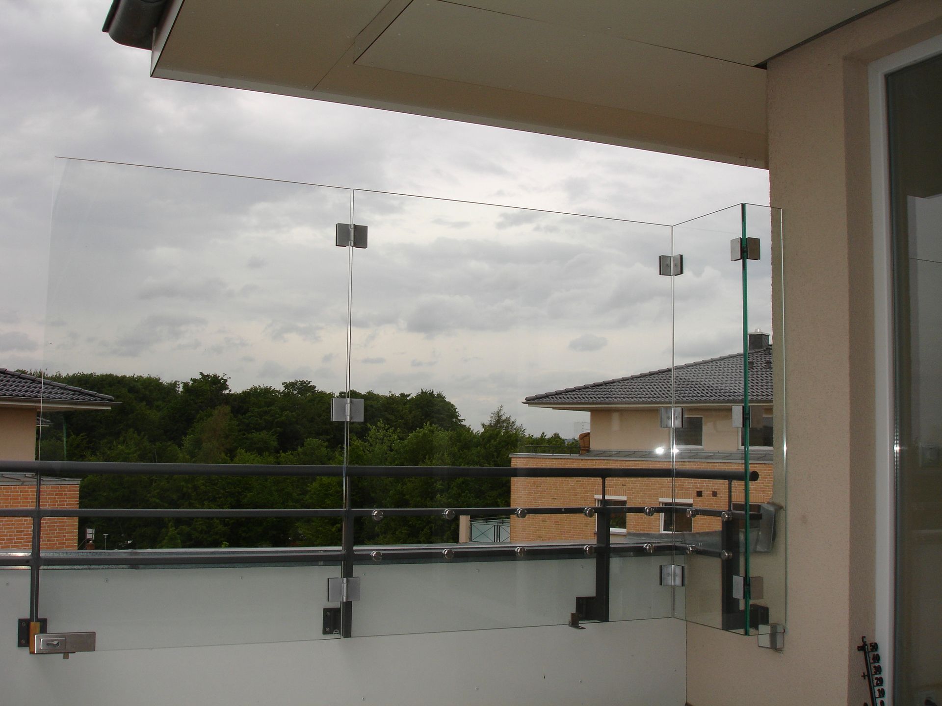 Ein Balkon mit Glasgeländer und Bäumen im Hintergrund