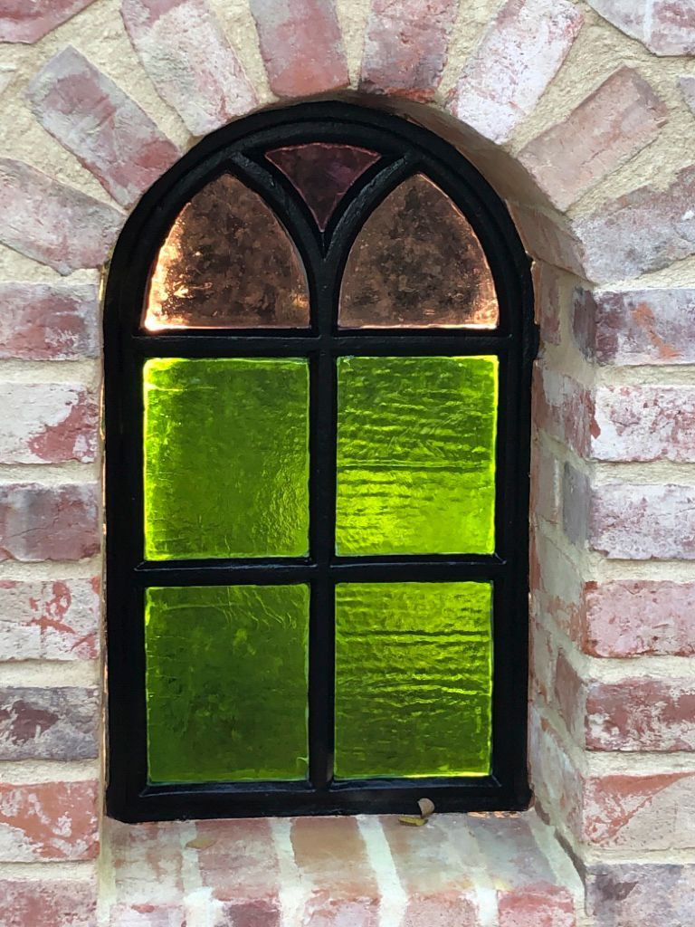 Eine Backsteinmauer mit einem Buntglasfenster in der Ecke