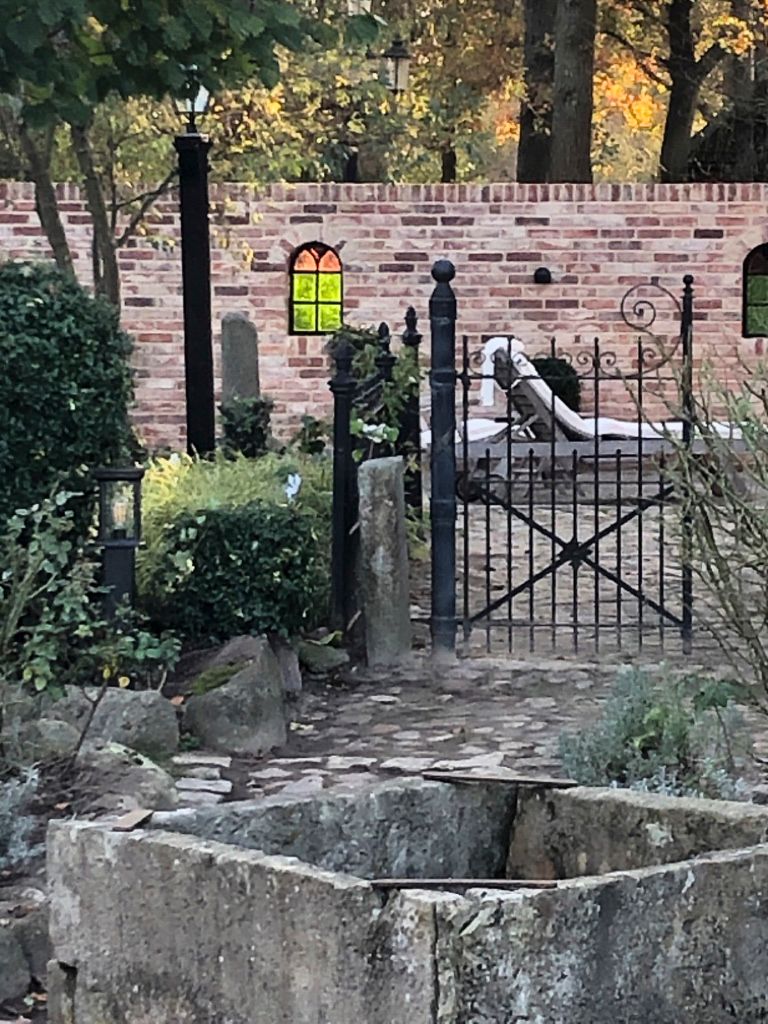 Eine Backsteinmauer mit einem Tor und einer Statue davor