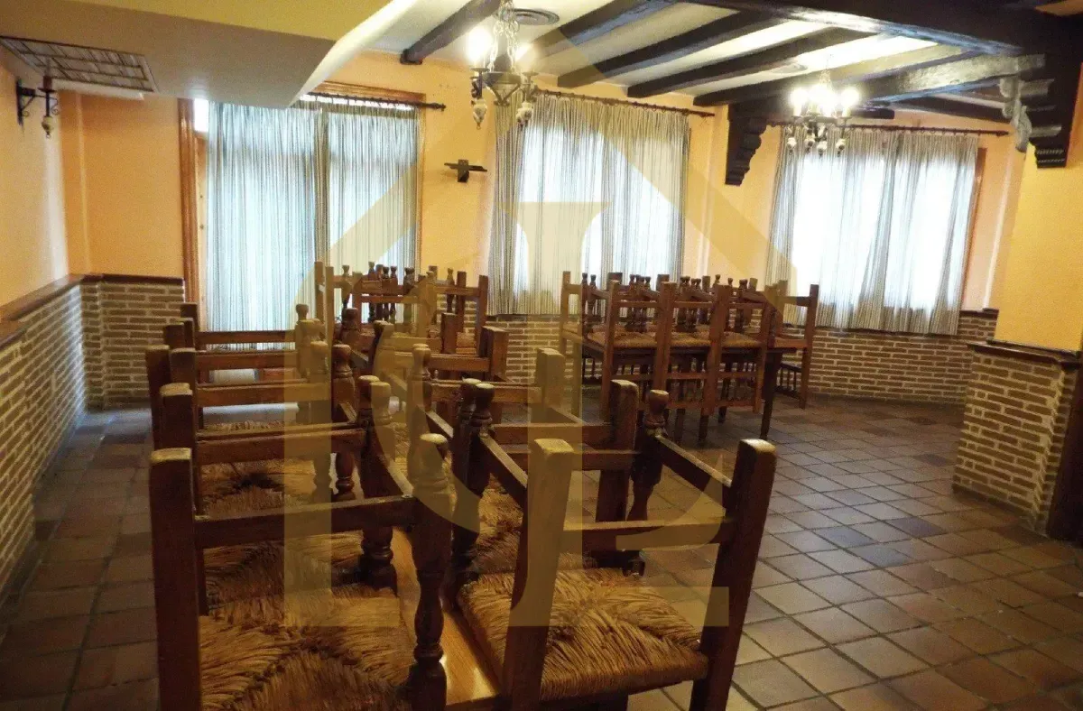 Comedor vacío con mesas y sillas de madera, paredes color beige y detalles de ladrillo.