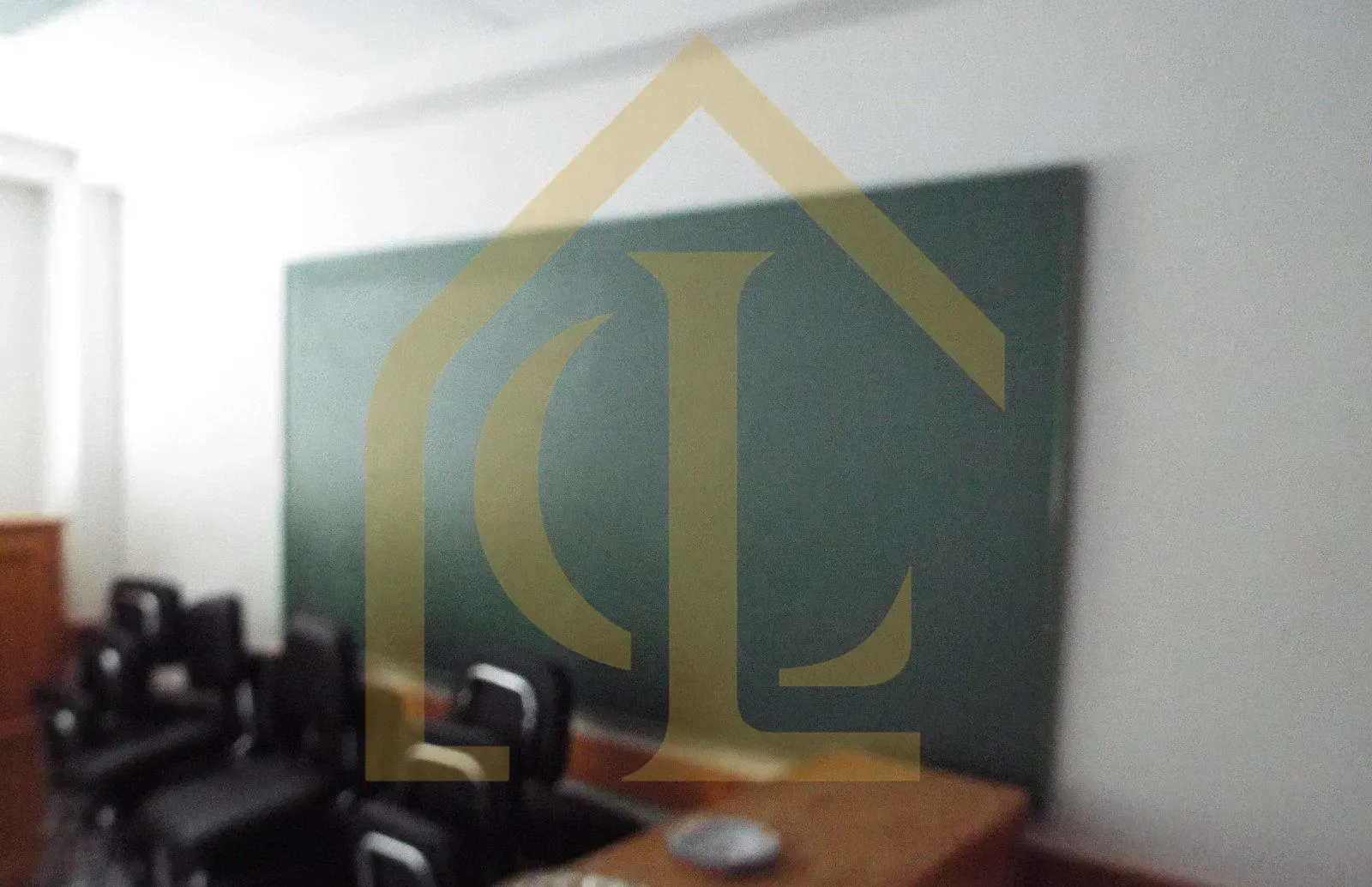 Aula vacía con una gran pizarra verde, sillas y mesa.