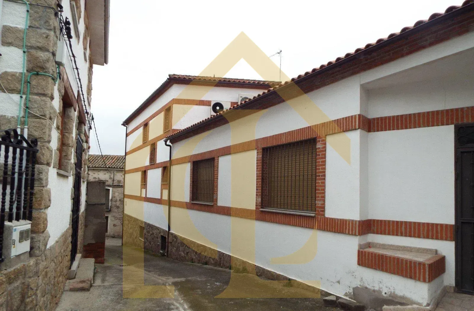 Edificio con fachada blanca y detalles de ladrillo en una calle estrecha.