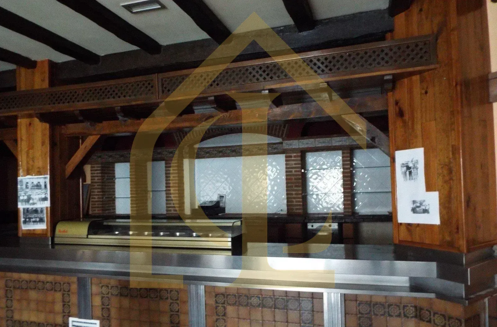 Barra de madera con vitrina, vigas superiores y ladrillo visto.