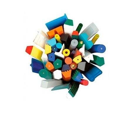 Surtido colorido de formas y objetos de plástico, incluidos pinceles, bloques geométricos y mangos, esparcidos sobre un fondo blanco.