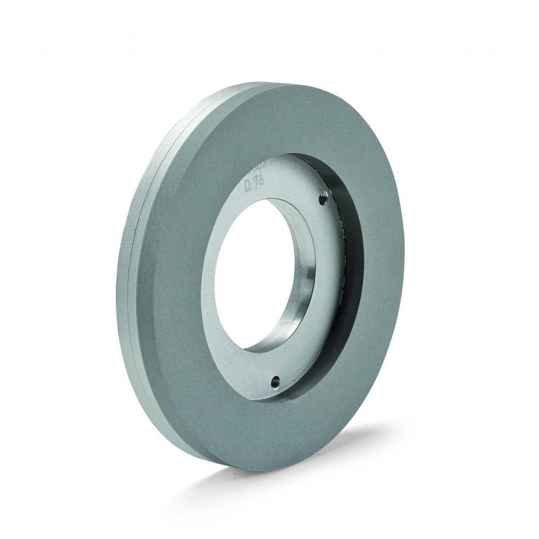 Una muela circular gris con un agujero centrado y un cubo metálico. Se encuentra sobre un fondo blanco.