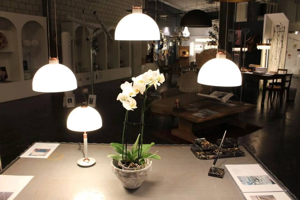 Restauranttisch mit leuchtend weissen Pendelleuchten und einer weissen Orchidee im Topf in der Mitte