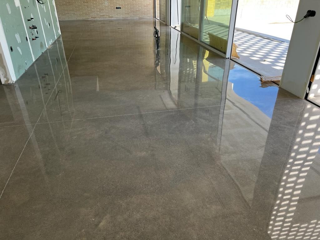 Un suelo de hormigón brillante en una habitación con el reflejo de un edificio.