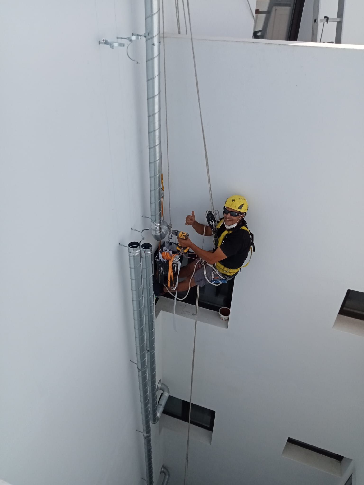 Un hombre está trabajando en una tubería en el costado de un edificio.