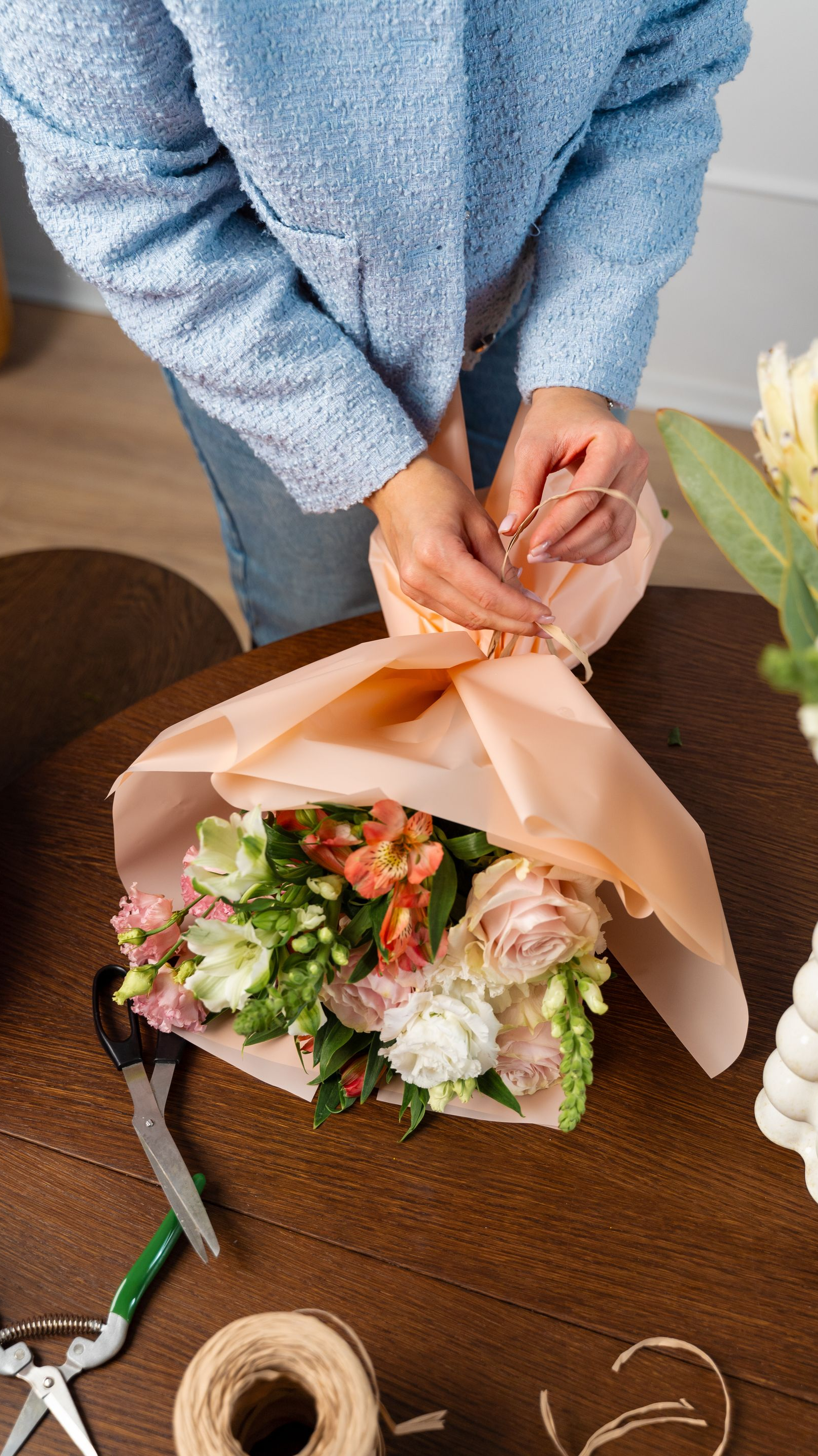 Personne en train de faire un bouquet de fleurs avec une veste bleue