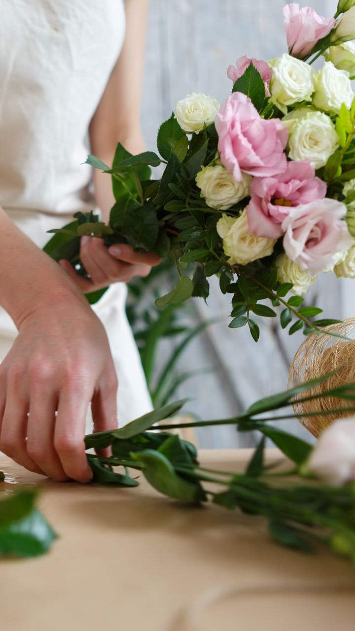 Personne en train de faire un bouquet de fleurs roses et blanches