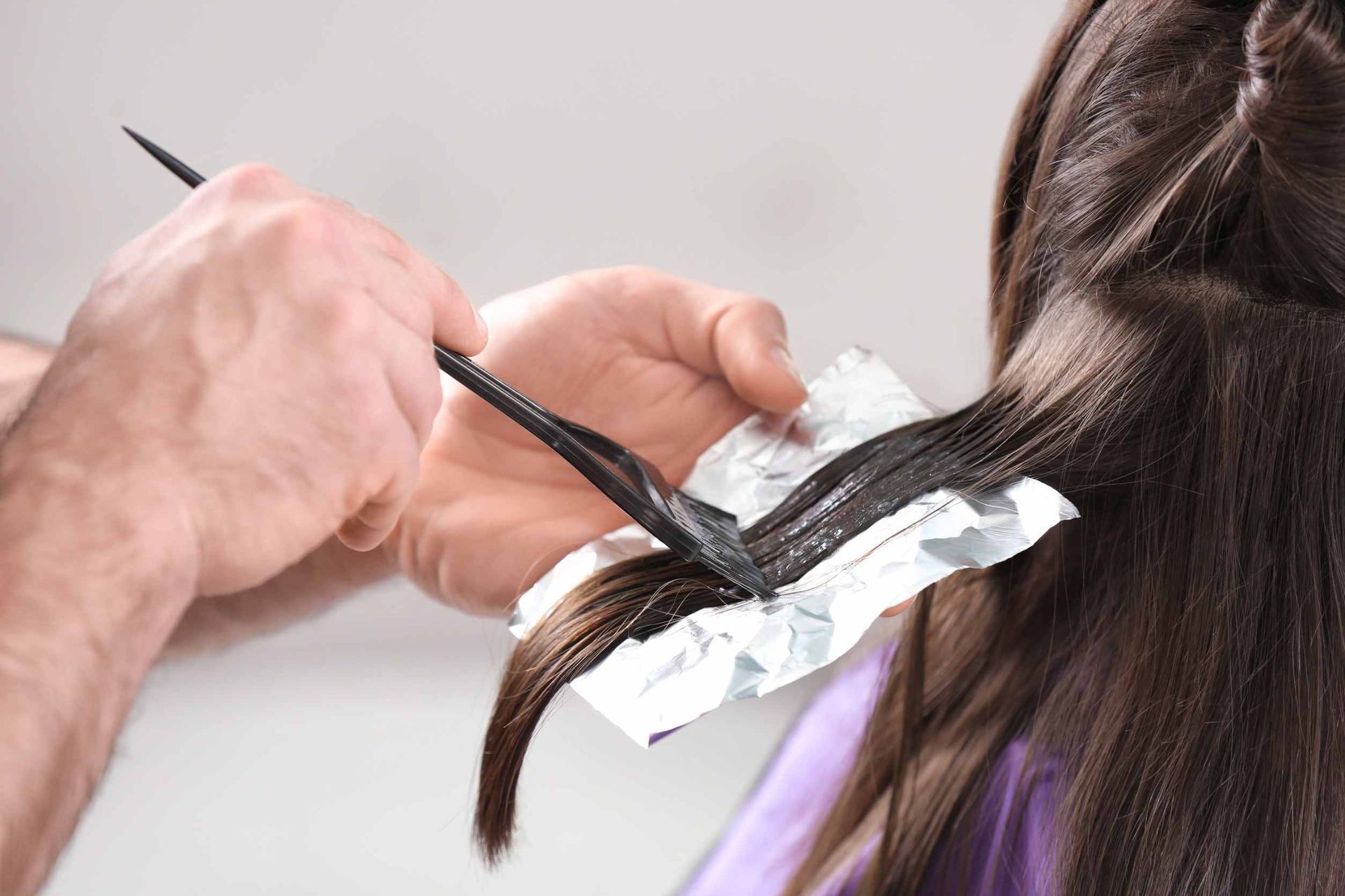 Una mujer se está tiñendo el pelo en la peluquería.