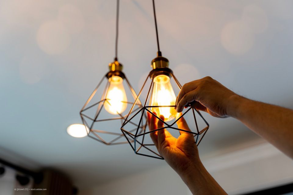 Elektro Wölfle – zwei Hände beim Einsetzen einer Glühbirne in eine Deckenlampe