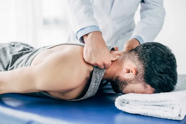 Un hombre está acostado en una mesa recibiendo un masaje de un médico.