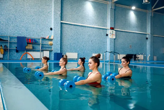 Un grupo de mujeres está haciendo aeróbic acuático en una piscina.