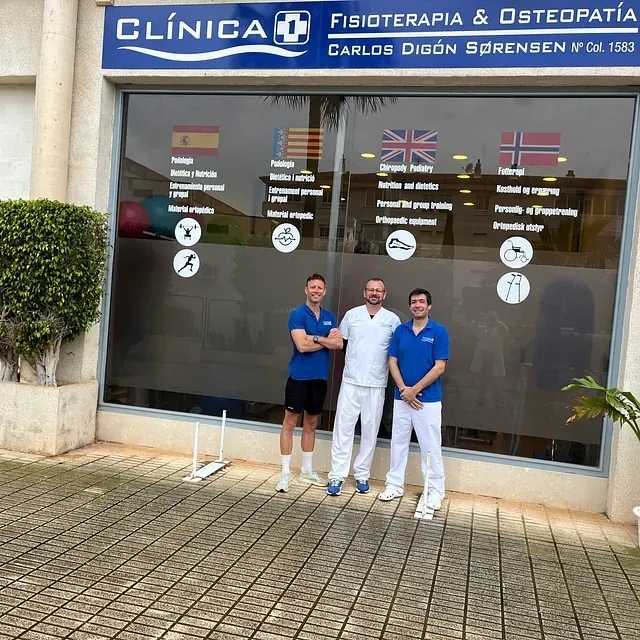 Tres hombres se encuentran frente a la Clínica de Fisioterapia y Osteopatía.