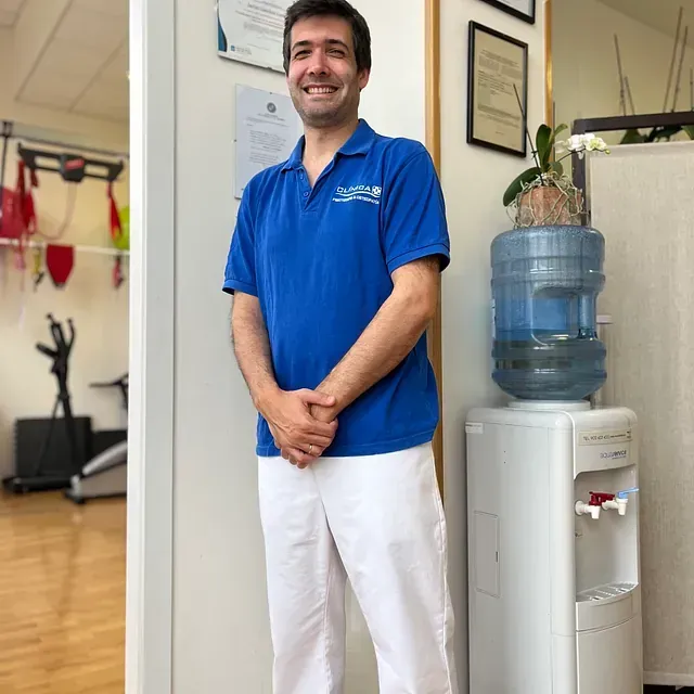 Un hombre con una camisa azul está de pie junto a un dispensador de agua.