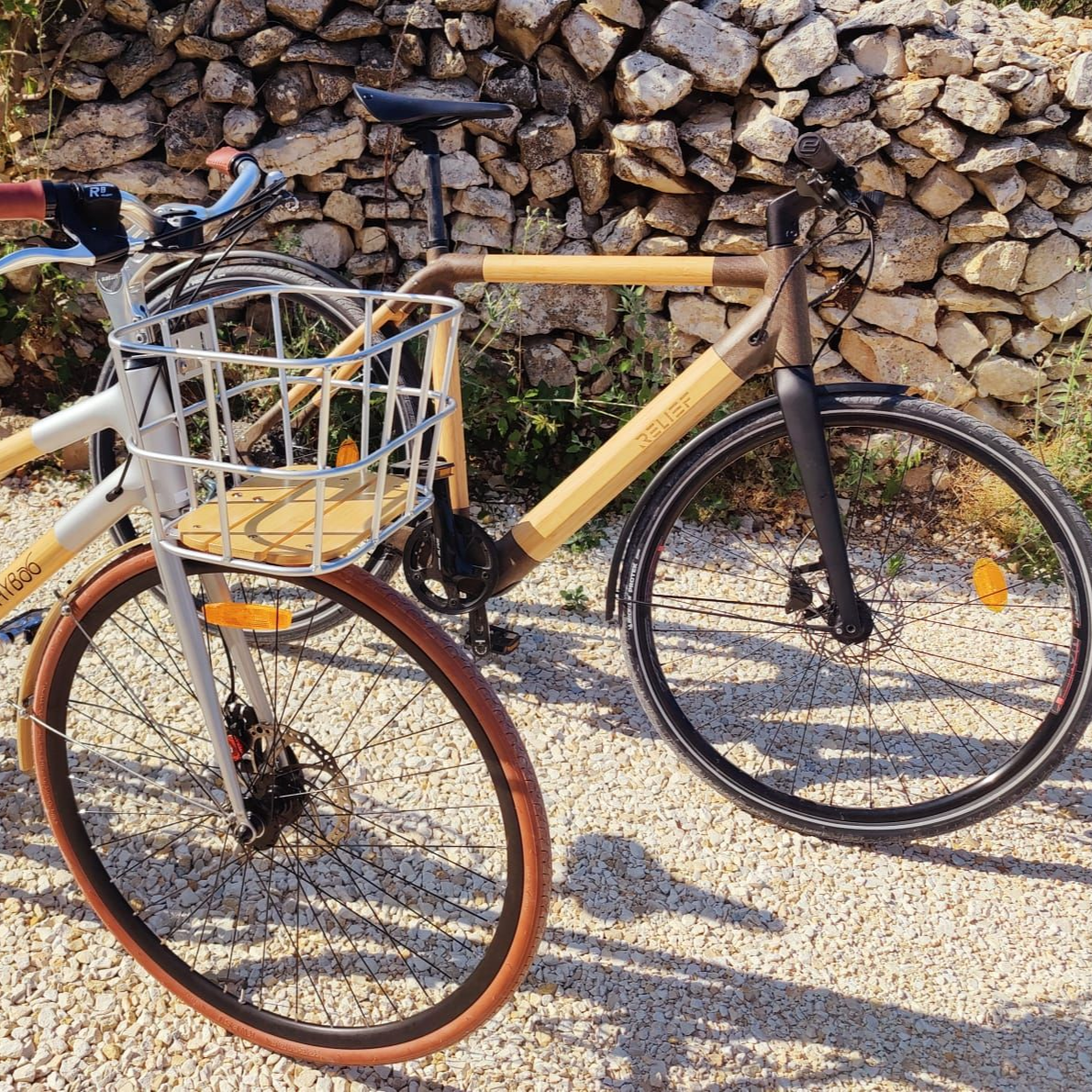 Vélo électrique bleu et beige avec panier garé à côté de la verdure ; vignes en arrière-plan.