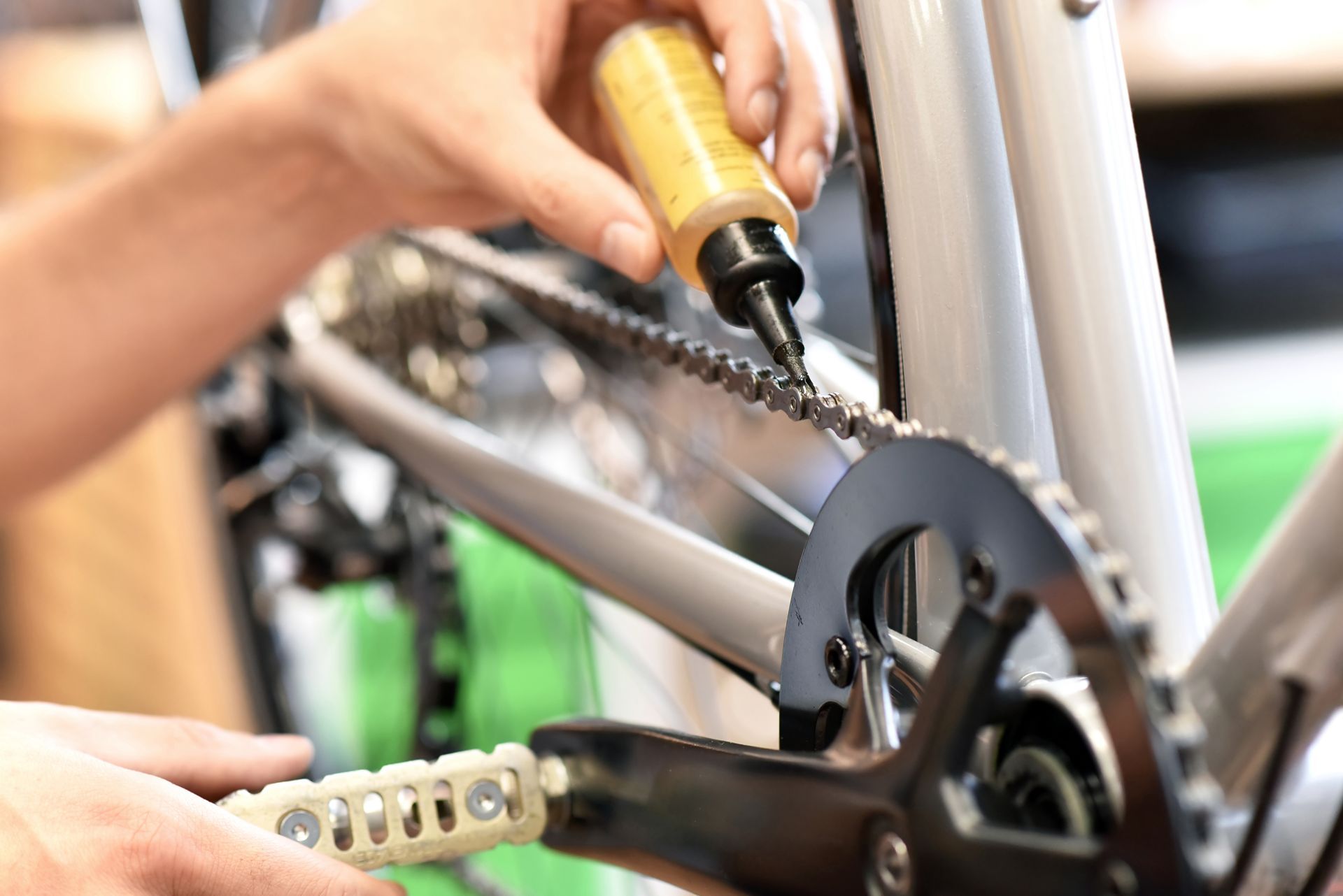 Personne lubrifiant une chaîne de vélo avec une bouteille d'huile.