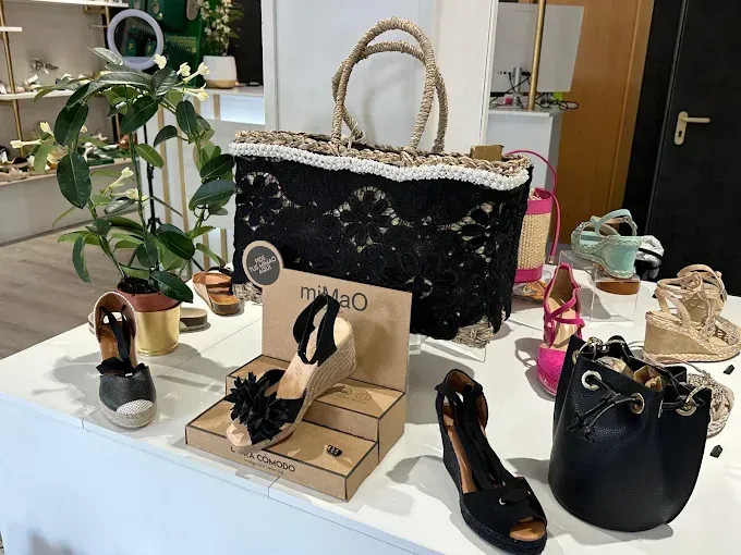 Una exhibición de zapatos y bolsos en una mesa en una tienda.