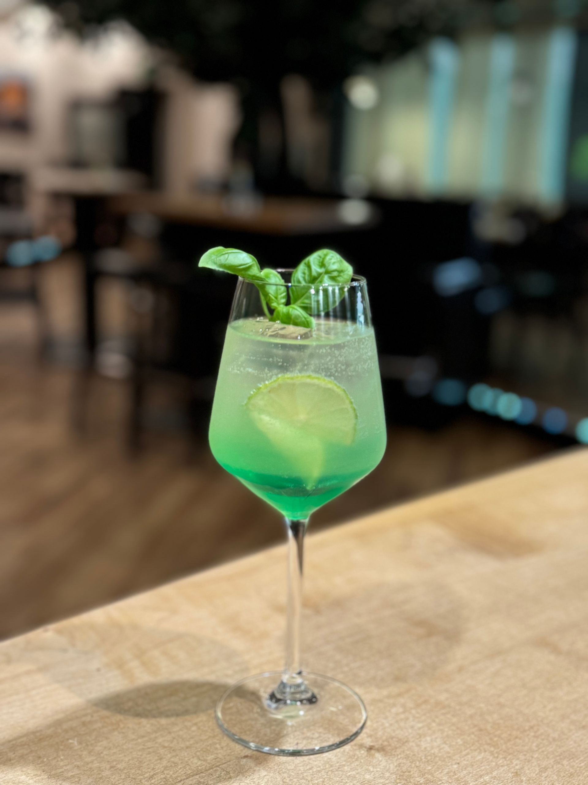 Ein grünes Getränk in einem Weinglas auf einem Tisch.