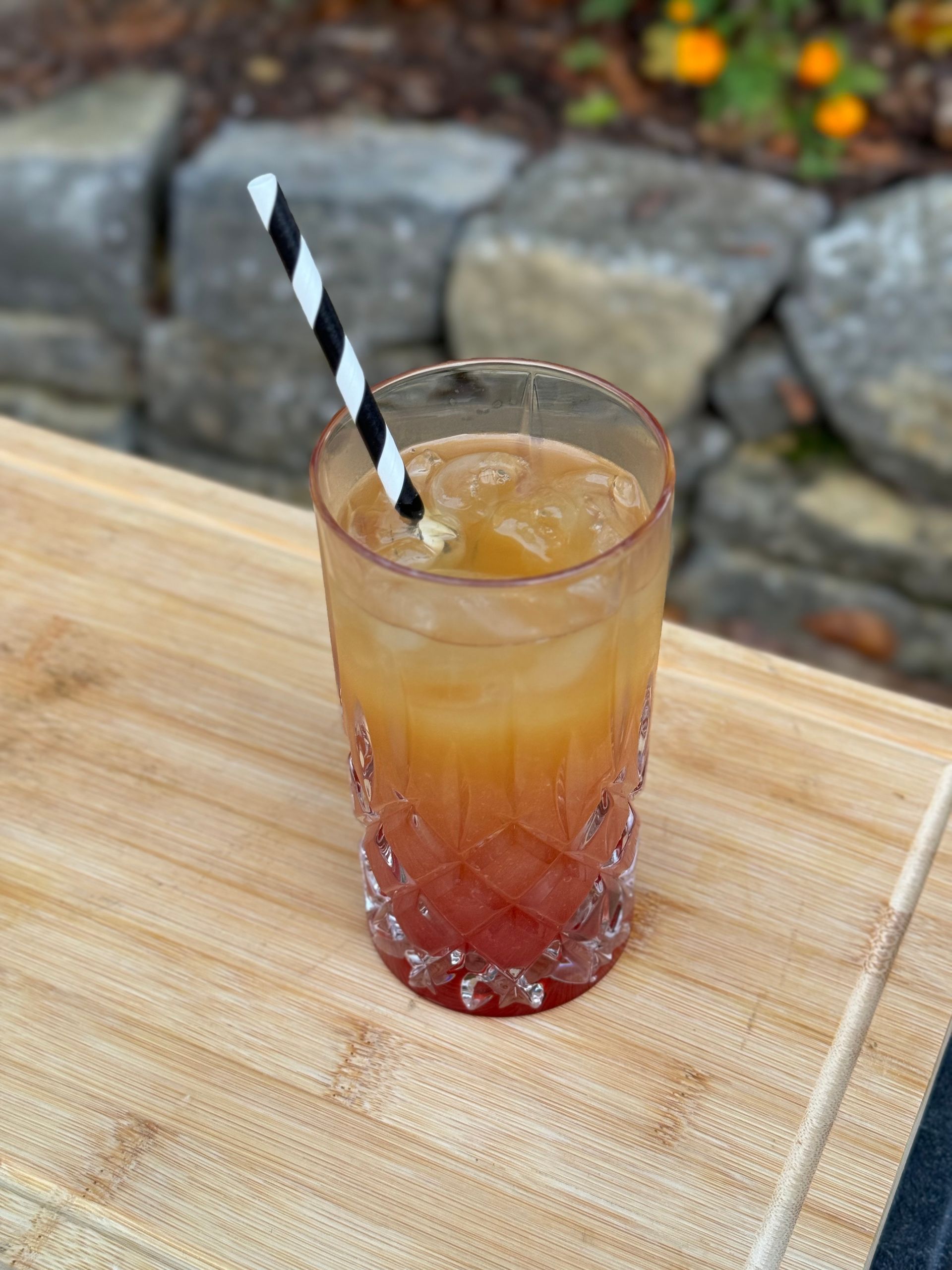 Ein Glas Eistee mit einem Strohhalm auf einem Holztisch.