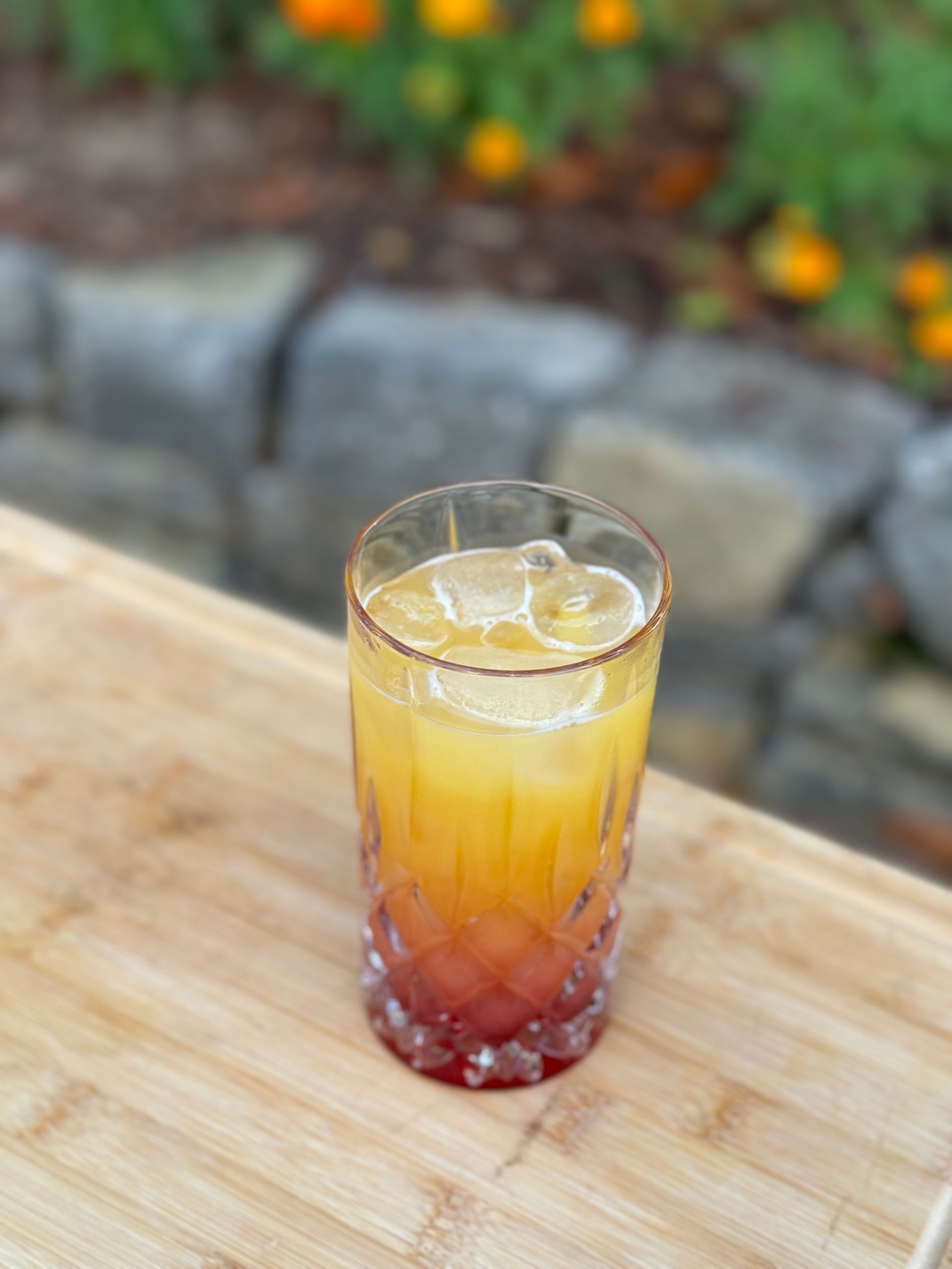 Ein Glas Orangensaft steht auf einem Holztisch.