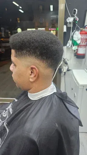 Una persona con un corte de pelo corto y texturizado con degradado, sentada en 