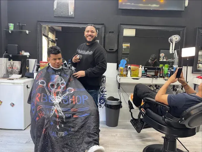 Un peluquero sonríe mientras le corta el pelo a un cliente en una peluquería