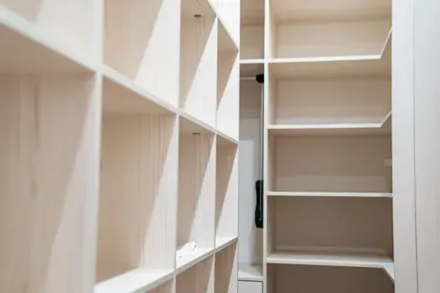 Armario de madera vacío con estantes y cubículos empotrados, pintado de blanco.