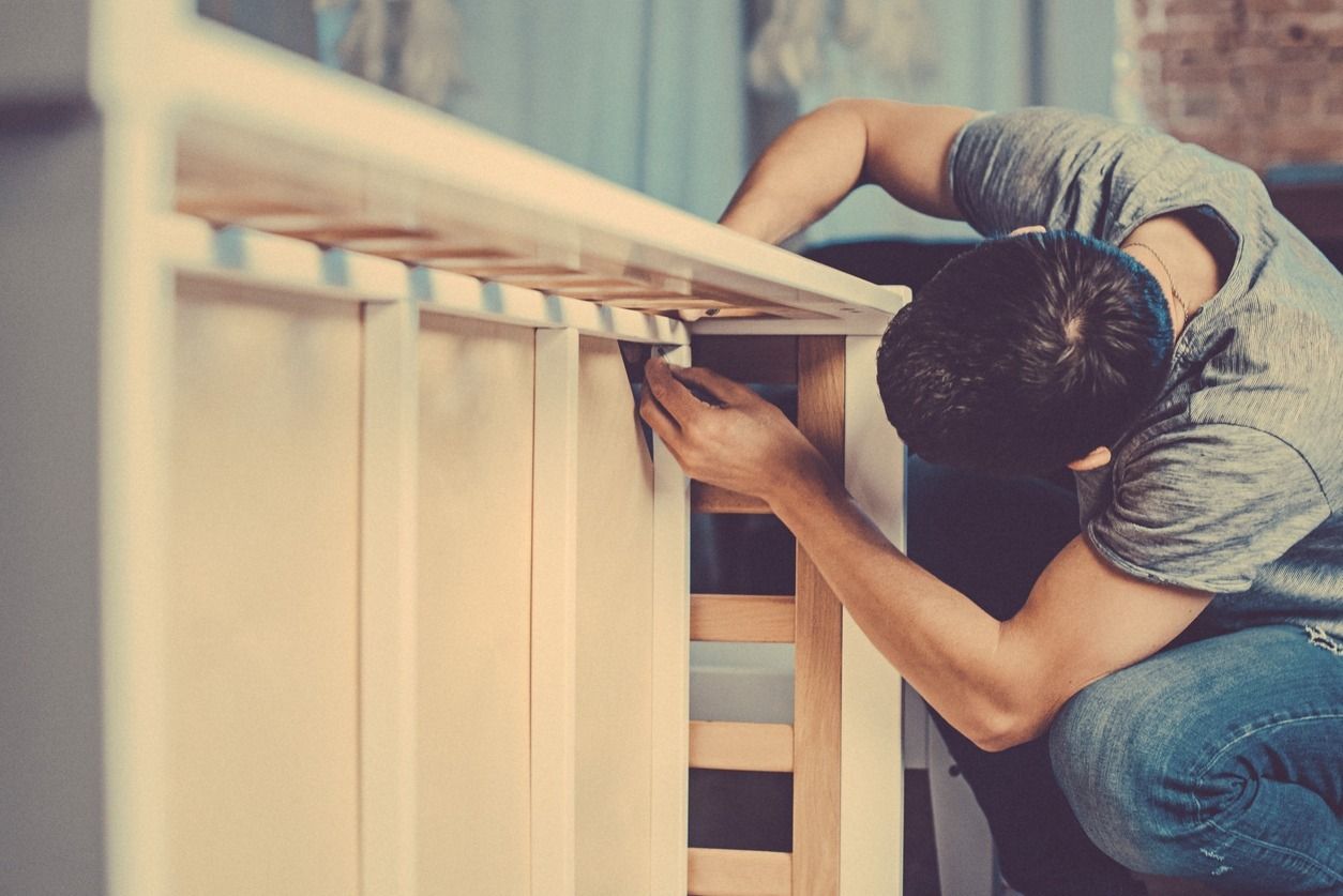 Hombre ensamblando muebles de madera en el interior.