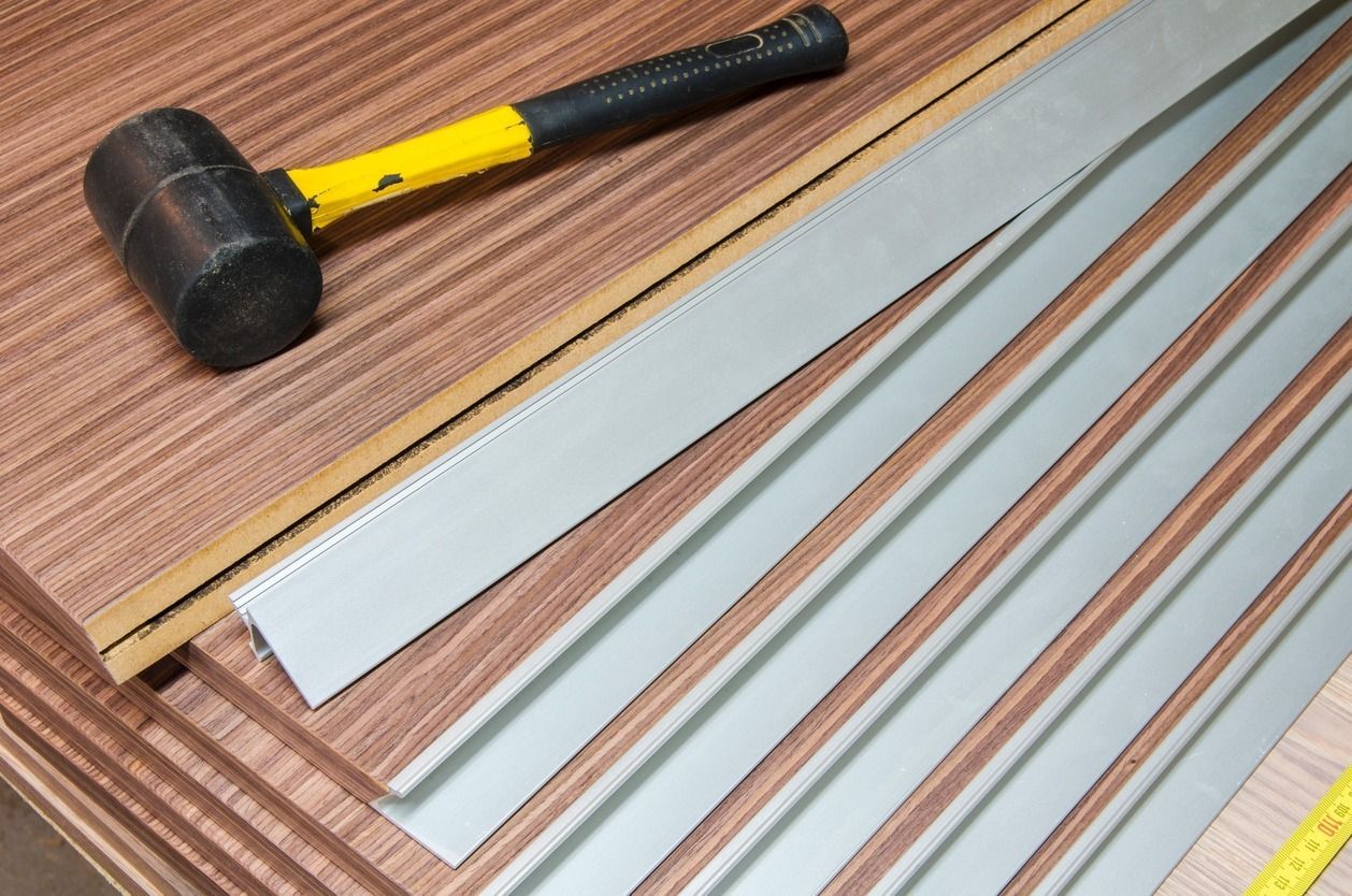 Tablones de madera, un mazo y tiras de metal sobre una superficie de madera, listos para trabajar la madera.